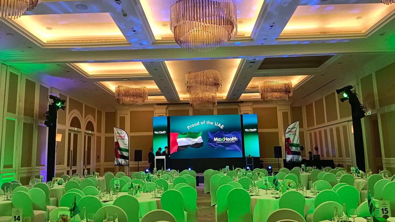 Corporate conference room with a wide LED stage and banquet seating