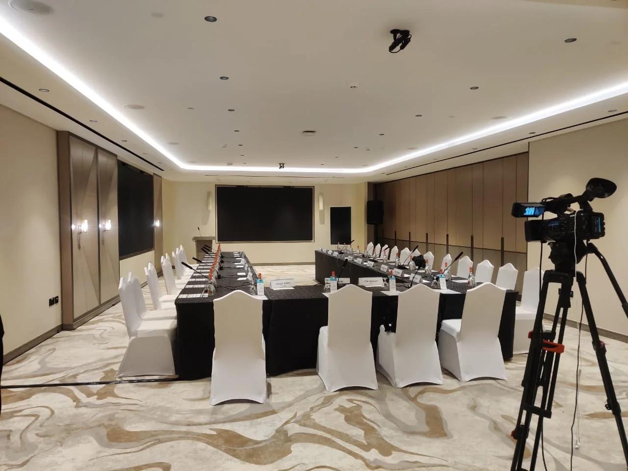 Broadcast camera positioned beside a conference room during production