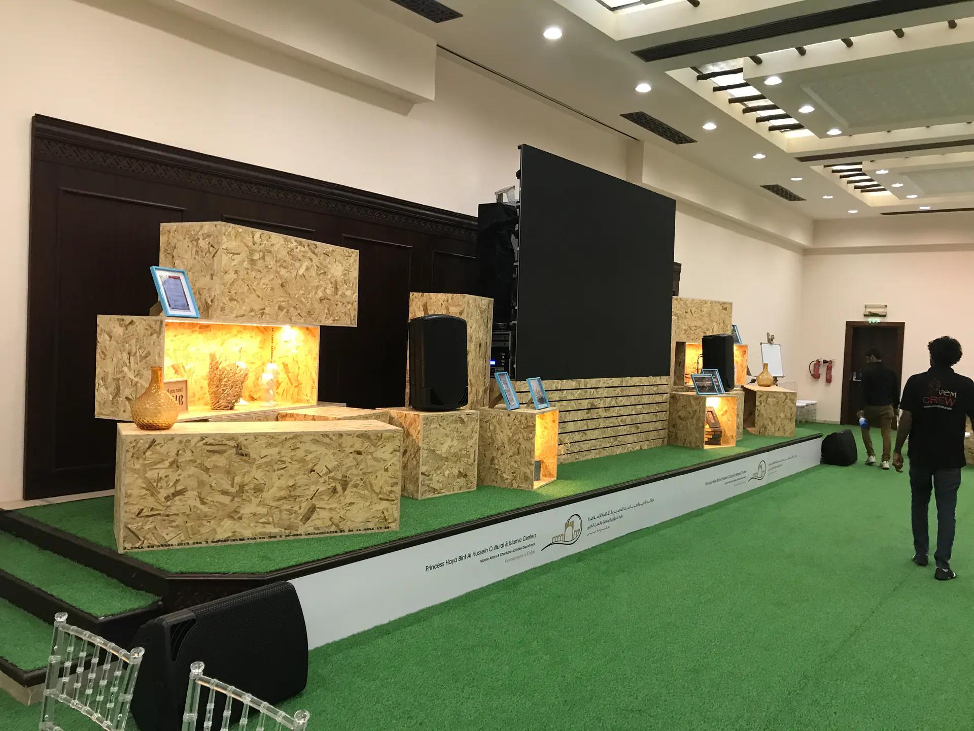 Custom timber display stage with illuminated shelving and a central screen.