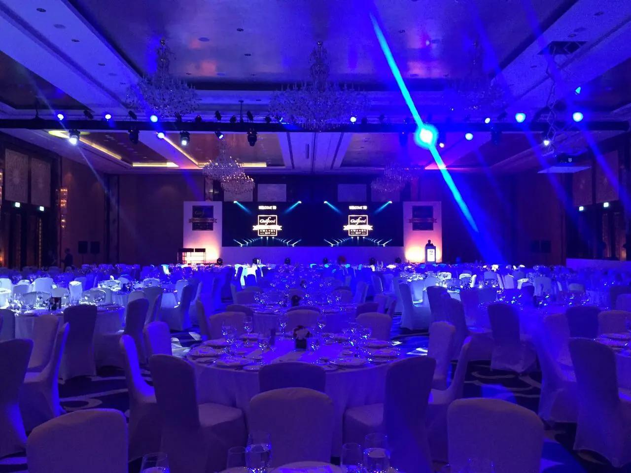Stage beams and overhead lighting fixtures operating in a live event hall.